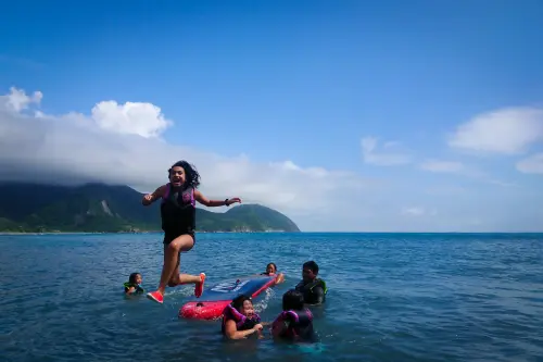 Camper jumping off a bodyboard into the ocean with mountains behind