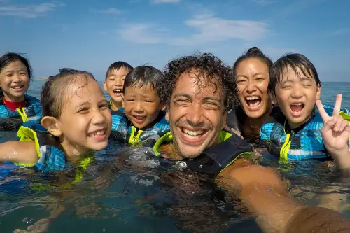 Camp leader and kids laughing together while swimming in the ocean
