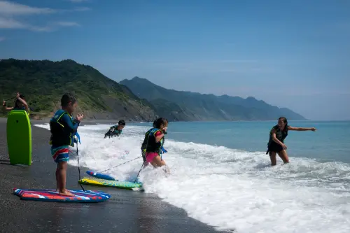 Kids bodyboarding in the waves at a Hualien beach