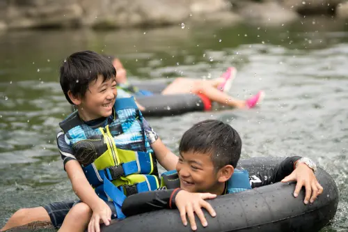 Laughing kids splashing on inner tubes in the river
