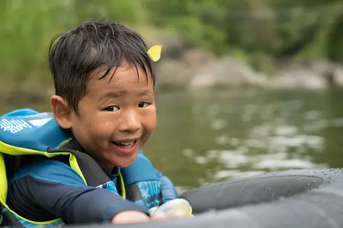 Young camper smiling on an inner tube with a butterfly on his head